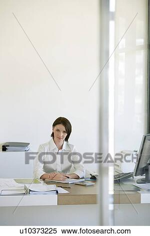 Businesswoman sitting at desk in office front view. View Large Photo Image Stock Photography - Businesswoman sitting at desk in office front view.. Fotosearch