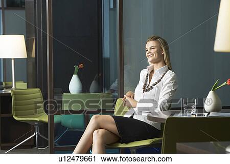 Stock Image - Businesswoman sitting in office smiling portrait. Fotosearch