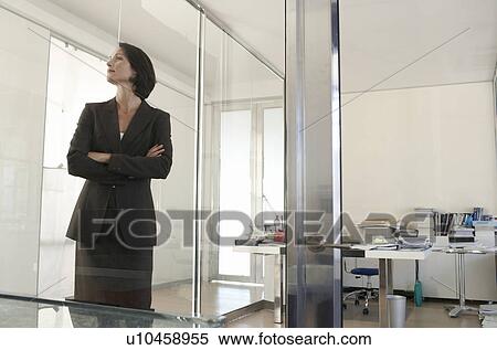Stock Photography - Businesswoman standing in office front view.. Fotosearch