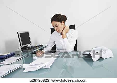 Stock Image - Businesswoman working at desk in office. Fotosearch