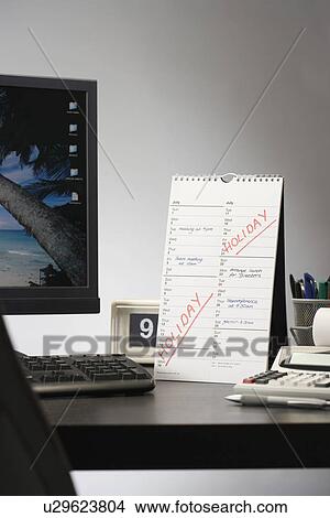 Calendar with marked holiday time on desk in office View Large Photo Image Picture - Calendar with marked holiday time on desk in office. Fotosearch