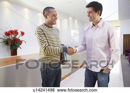 Casually dressed Businessmen smiling Shaking Hands in Office View Large Photo Image Stock Photo - Casually dressed Businessmen smiling Shaking Hands in Office. Fotosearch