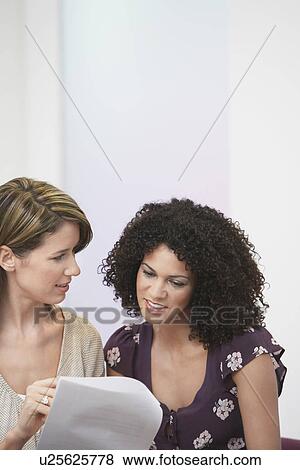 Stock Photo - Casually dressed Businesswomen going over Document. Fotosearch