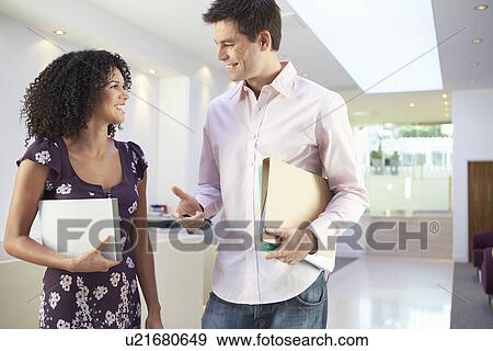 Casually dressed office workers standing talking in office View Large Photo Image Stock Photo - Casually dressed office workers standing talking in office. Fotosearch