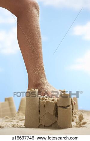 Stock Photograph - Child stepping on sand castle low section. Fotosearch