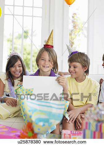 Stock Image - Chlidren (7-12) watching one boy open birthday presents. Fotosearch