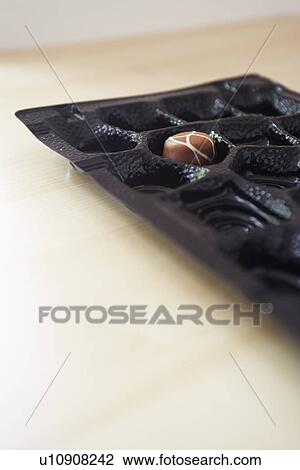 Stock Image - Chocolate box with only one truffle remaining close-up. Fotosearch