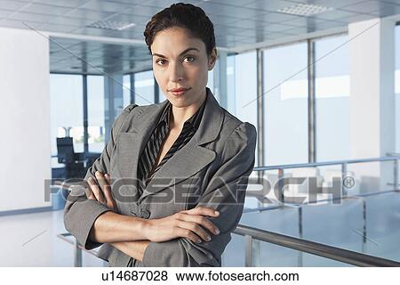 Stock Photo - Confident businesswoman standing in office corridor. Fotosearch