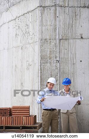 Stock Photo - Construction manager and architect examining plans on site. Fotosearch
