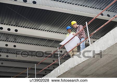 Construction manager and worker examining building plans View Large Photo Image Stock Photo - Construction manager and worker examining building plans. Fotosearch
