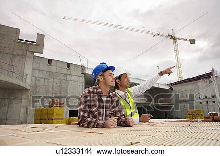 Picture - Construction workers discussing job. Fotosearch