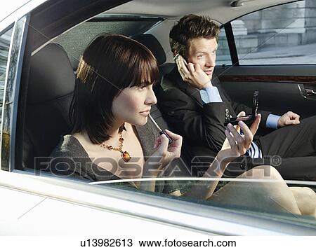 Couple at back seat of car woman applying make-up man using mobile phone View Large Photo Image Stock Image - Couple at back seat of car woman applying make-up man using mobile phone. Fotosearch