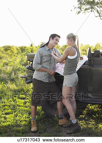 Stock Image - Couple by jeep woman adjusting man's shirt. Fotosearch
