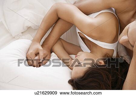 Stock Photo - Couple embracing in bed half length. Fotosearch