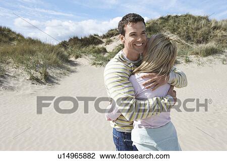 Stock Image - Couple embracing on beach. Fotosearch