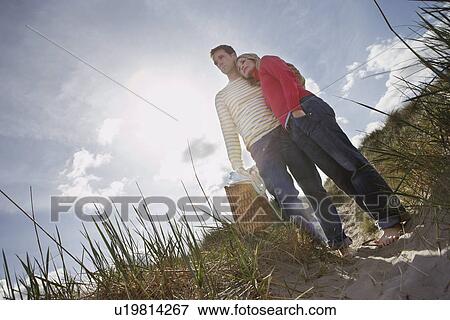 Stock Photo - Couple embracing on sand dune. Fotosearch