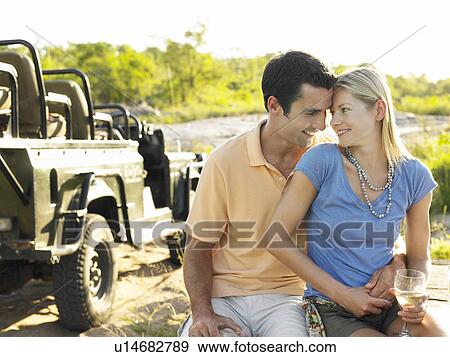 Couple embracing outdoors looking in eyes jeep in background View Large Photo Image Stock Photo - Couple embracing outdoors looking in eyes jeep in background. Fotosearch