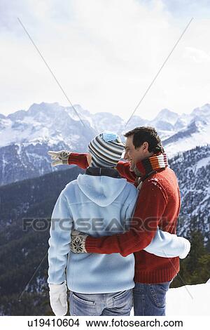 Picture - Couple looking at view from mountain peak back view. Fotosearch