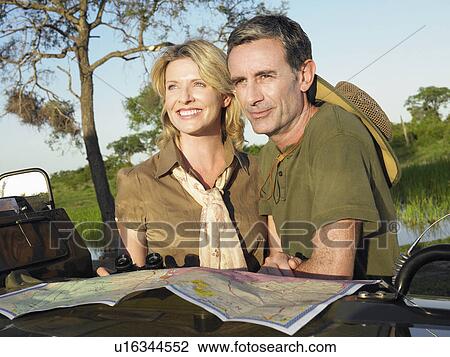 Couple looking at view map spread on bonnet of jeep View Large Photo Image Stock Image - Couple looking at view map spread on bonnet of jeep. Fotosearch