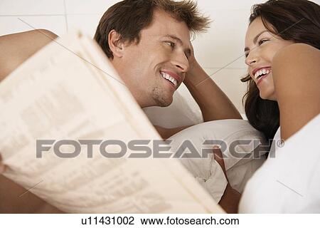 Couple lying in bed reading newspaper head and shoulders View Large Photo Image Stock Image - Couple lying in bed reading newspaper head and shoulders. Fotosearch