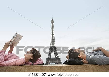 Stock Photo - Couple lying on ledge of the Trocadero with Eiffel Tower viewed in the background. Fotosearch