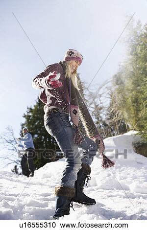 Stock Image - Couple playing in snow on hill low angle view. Fotosearch