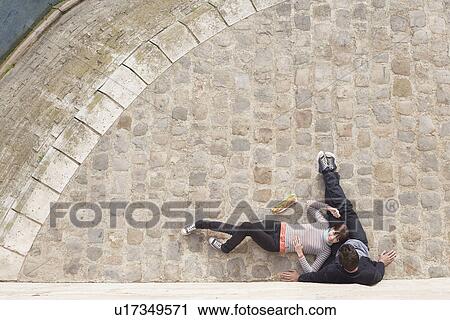 Stock Image - Couple Relaxing on cobble stones view from above. Fotosearch
