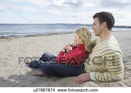 Couple sitting on beach embracing View Large Photo Image Picture - Couple sitting on beach embracing. Fotosearch