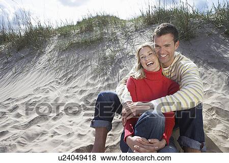 Couple sitting on beach embracing View Large Photo Image Stock Photo - Couple sitting on beach embracing. Fotosearch