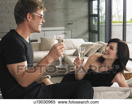 Stock Photography - Couple sitting with champagne in living room. Fotosearch