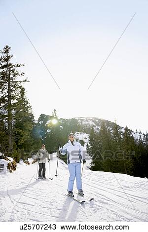 Stock Image - Couple skiing down slope. Fotosearch
