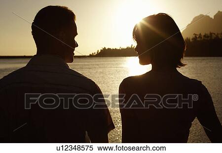 Stock Photography - Couple standing by lake back view.. Fotosearch