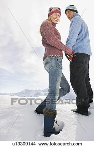 Couple standing on snow covered hill portrait low angle view View Large Photo Image Picture - Couple standing on snow covered hill portrait low angle view. Fotosearch