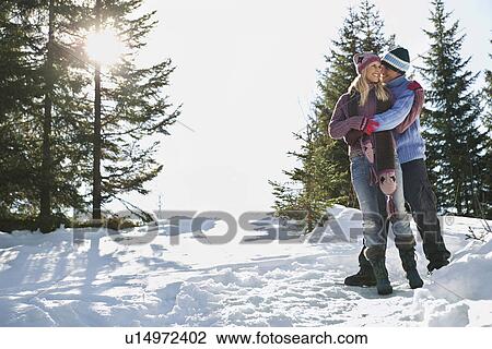 Couple standing on snow-covered hill View Large Photo Image Stock Image - Couple standing on snow-covered hill. Fotosearch