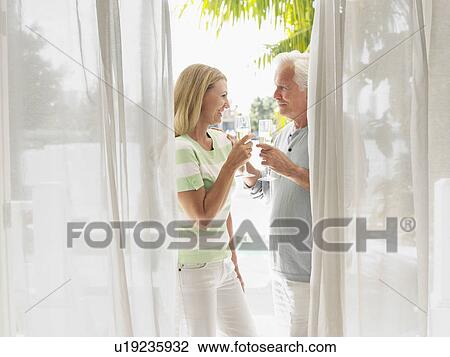 Couple toasting with champagne flutes standing on verandah side view View Large Photo Image Stock Image - Couple toasting with champagne flutes standing on verandah side view. Fotosearch