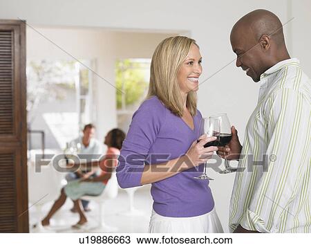 Stock Image - Couple toasting with wineglasses at home. Fotosearch