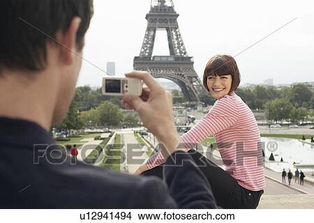 Picture - Couple Using Camera Phone and Eiffel Tower. Fotosearch