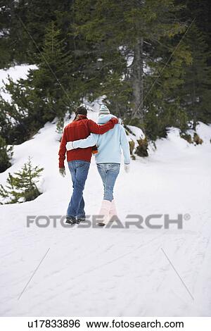 Stock Photograph - Couple walking on snow-covered path back view. Fotosearch