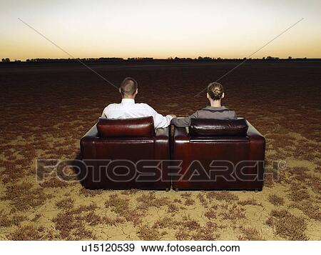 Couple watching sunset sitting in armchairs in open plain back view View Large Photo Image Stock Photo - Couple watching sunset sitting in armchairs in open plain back view. Fotosearch