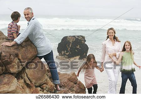 Stock Image - Family with three children (5-6 7-9 10-12) on beach. Fotosearch