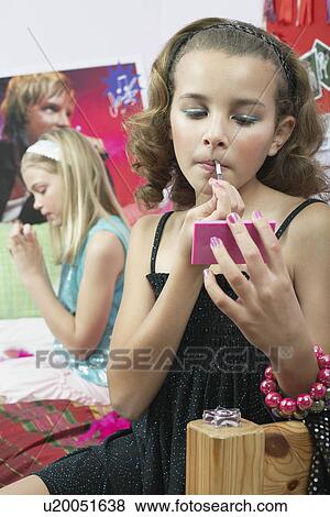 Stock Photo - Fashionable Young Girls Applying Makeup in trendy bedroom. Fotosearch
