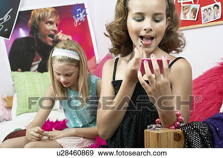 Stock Photo - Fashionable Young Girls Applying Makeup in trendy bedroom. Fotosearch
