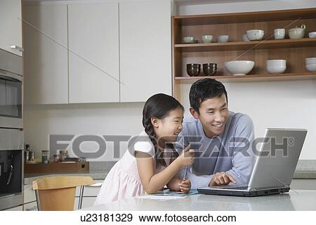 Father and daughter playing with laptop on kitchen counter View Large Photo Image Stock Photo - Father and daughter playing with laptop on kitchen counter. Fotosearch