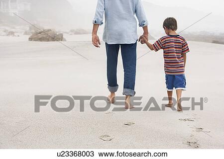 Father and son (5-6) holding hands walking on beach back view View Large Photo Image Stock Image - Father and son (5-6) holding hands walking on beach back view. Fotosearch