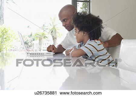 Father and son (5-6 years) using laptop on dining table side view View Large Photo Image Stock Image - Father and son (5-6 years) using laptop on dining table side view. Fotosearch