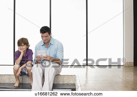 Father and son (7-9) sitting on floor indoors man playing handheld game View Large Photo Image Stock Image - Father and son (7-9) sitting on floor indoors man playing handheld game. Fotosearch