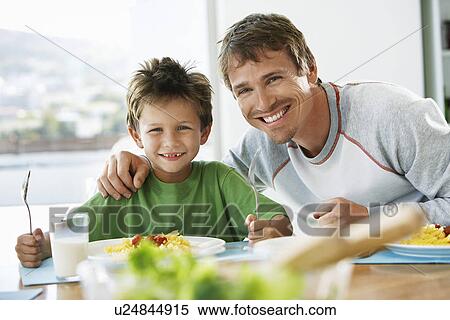 Father and son sitting at table eating pasta View Large Photo Image Stock Photography - Father and son sitting at table eating pasta. Fotosearch