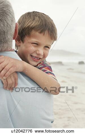 Father carrying son (5-6) on beach close-up View Large Photo Image Stock Photograph - Father carrying son (5-6) on beach close-up. Fotosearch