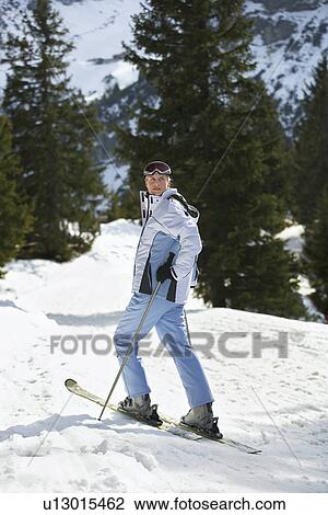 Stock Image - Female skier standing on ski slope. Fotosearch
