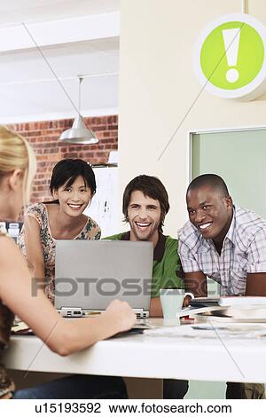 Four people having meeting around laptop laughing. View Large Photo Image Stock Image - Four people having meeting around laptop laughing.. Fotosearch